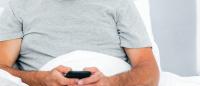 Stock image of Caucasian man looking holding a mobile phone.